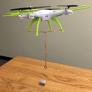 Unmanned aerial vehicle, or drone, picking up a small payload