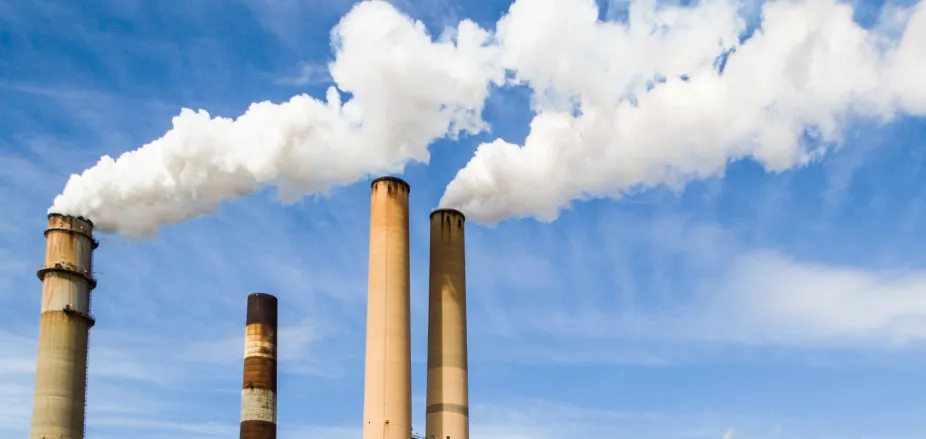 Four smokestacks with two releasing clouds of pollution into the air