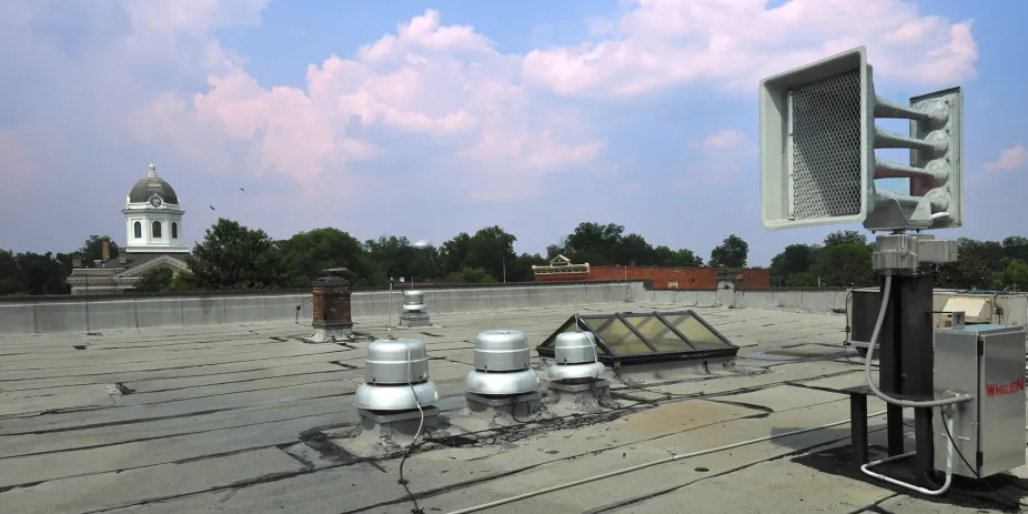 A large speaker of a tornado siren on a flat rooftop 