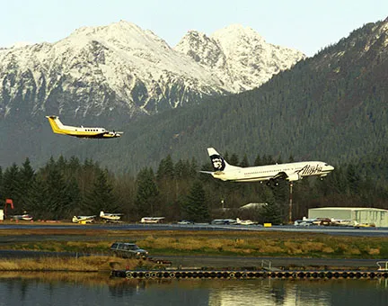 Photograph of an airplane taking off with mountains in immediate background