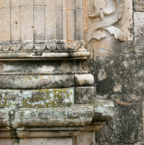 Stone features on a building are crumbling and damaged due to acid rain.