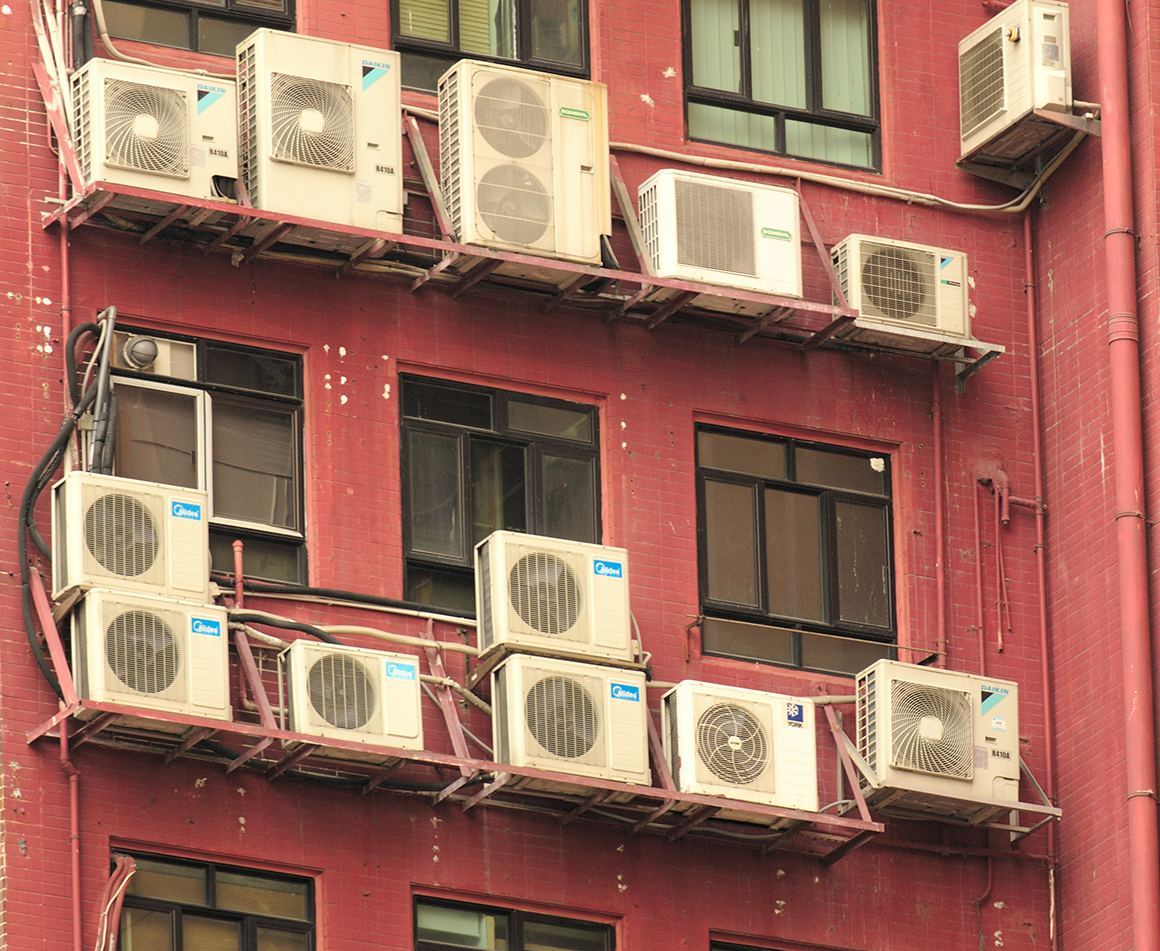This is a photo of of an apartment building with rows of window-unit air conditioners installed in the windows. 