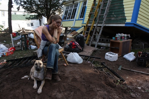 Anastasia Rikard and her dog in front of her damaged house