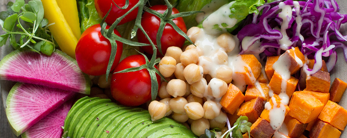 This is an image of tomatoes on the vine, chick peas, sliced avocados, carrots, and onions.