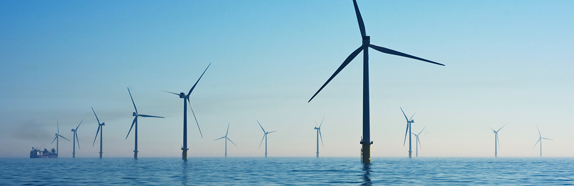 This is an image of several offshore wind turbines, with an ocean horizon.