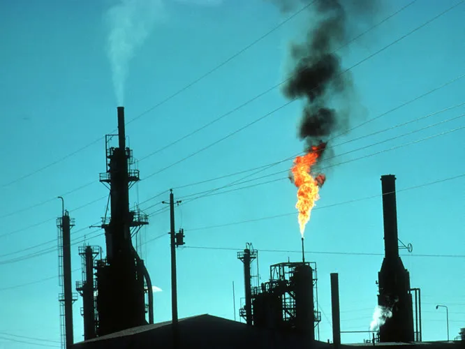 Smokestacks at an oil refinery emit several types of pollution into the air.