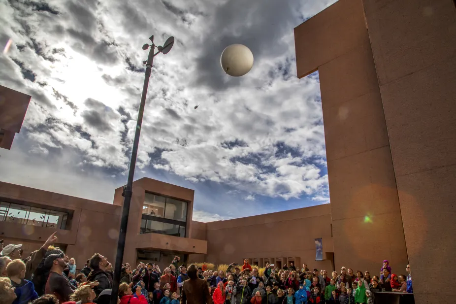 Visitors to NSF NCAR Mesa Lab look up in awe at a weather balloon launch at a Super Science Saturday event.
