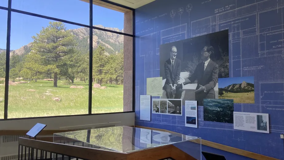 The north wall of the architecture exhibit with a photo of Walter Orr Roberts and I.M. Pei on the right side. There is a large window towards the flatirons on the left side.