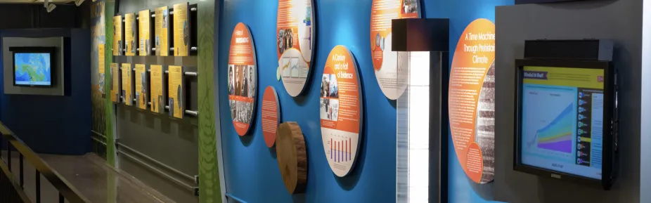 One wall of the Climate Exhibit showing wall signage, model of an ice core, and a cross section of tree rings.