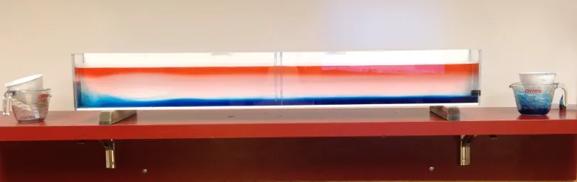 Tank full of water with red-dyed water floating on top and blue-dyed water sinking to the bottom
