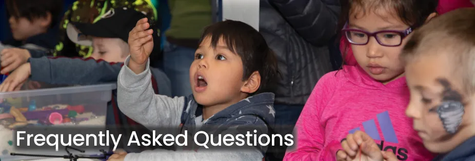 A photo of a student holding up an object and looking in awe at their discover. On top of the image is text that reads "Frequently Asked Questions".