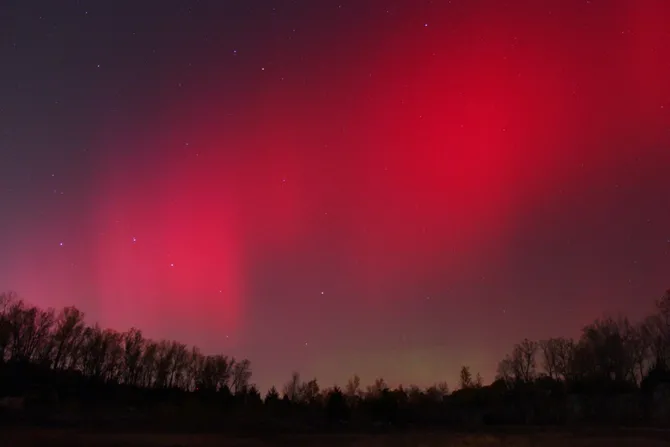 A band of glowing red lights in the sky above the horizon.