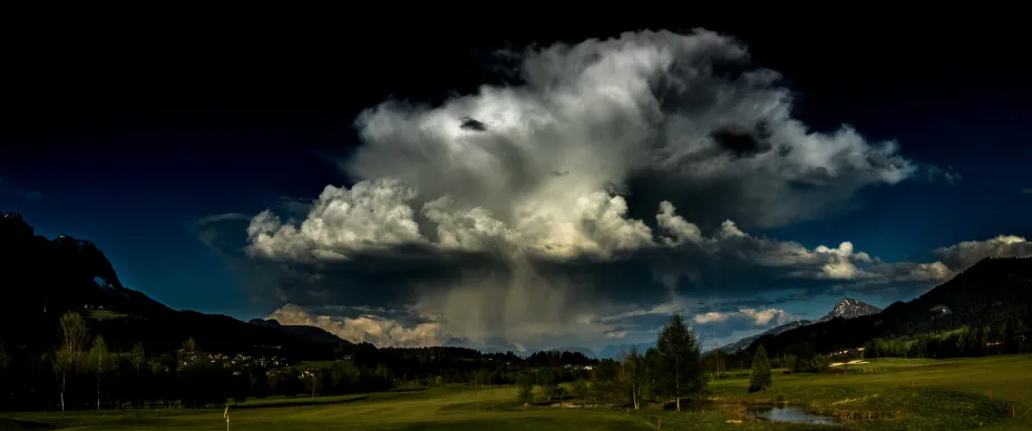 A cumulonimbus cloud causing rain in a mountain valley