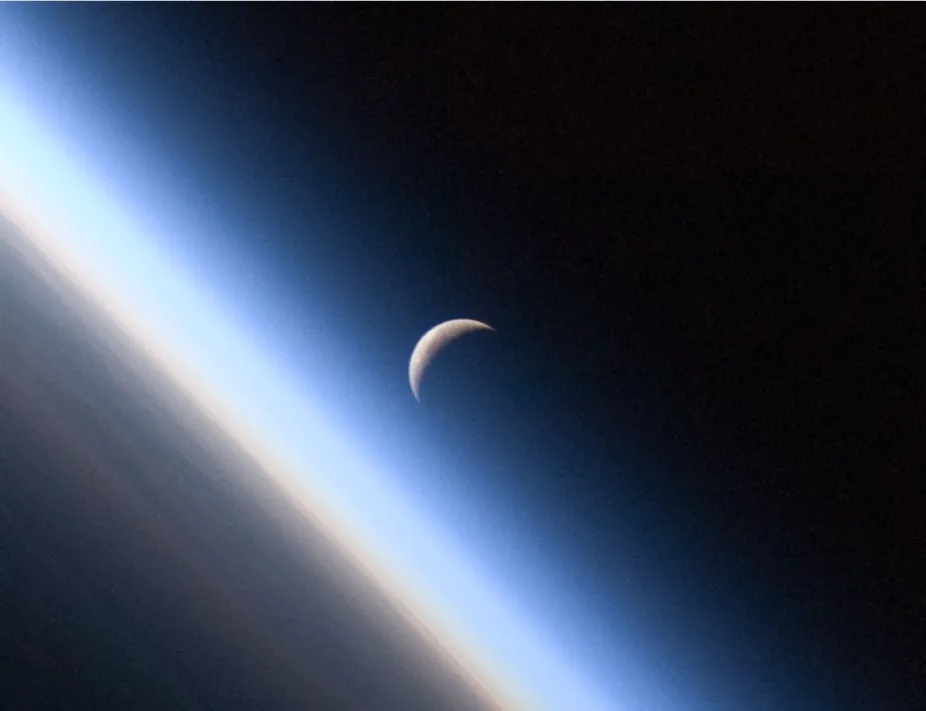 view of Earth's atmosphere visible from space as orangish and blue layers above Earth's surface