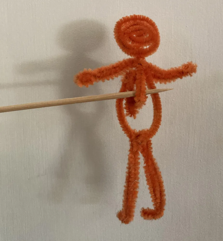 Example of a shadow puppet made out of orange pipe cleaners and a wooden skewer 