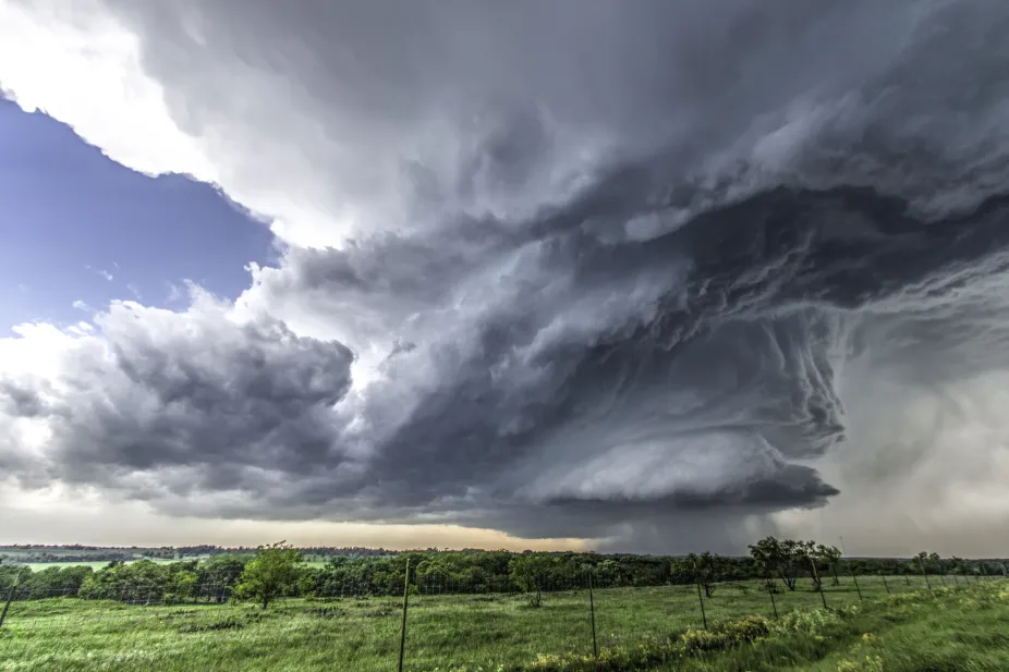 A large thunderstorm over flat grasslands. Rain is falling from the bottom of a towering cumulonimbus cloud.