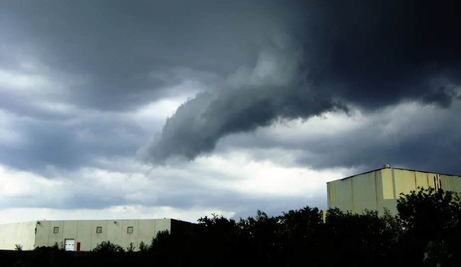 A dark funnel cloud coming out of storm clouds 