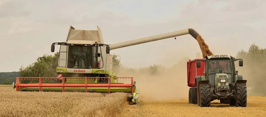 a combine harvests wheat and empties its load to a wagon