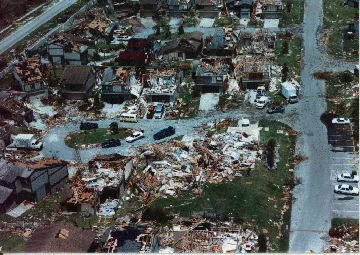 Aerial view of a neighborhood with several houses damaged or demolished by wind