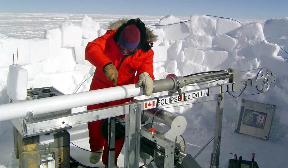 This is an image of an ice core drill and an ice core sample being examined by a researcher in the Arctic.