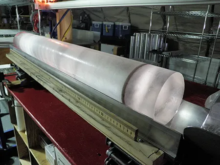 This is an image of an ice core that contains a dark band of volcanic ash towards the bottom of the core.