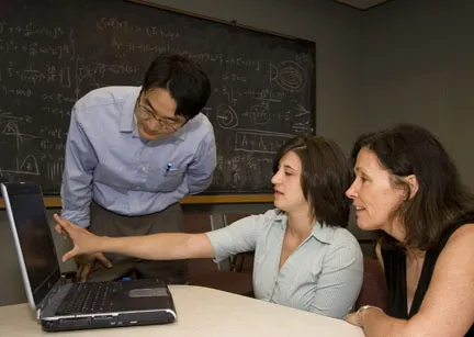 Three people looking at a laptop computer