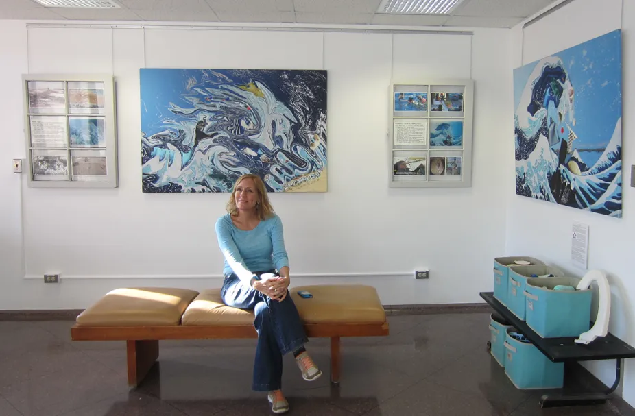 Artist sits in front of art exhibit at NCAR's Mesa Lab