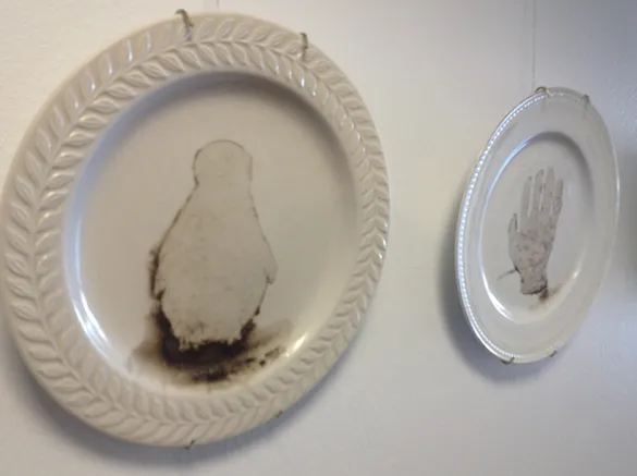 Dinner plate with an outline of a penguin (left) and child's hand (right)
