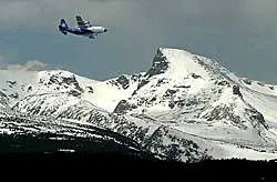 Airplane flying with snow-capped mountains in background