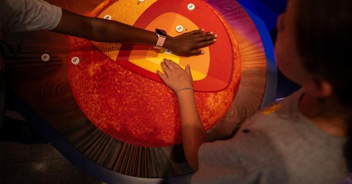 Students touching a graphic of the Sun's layers in the NSF NCAR Mesa Lab visitor center