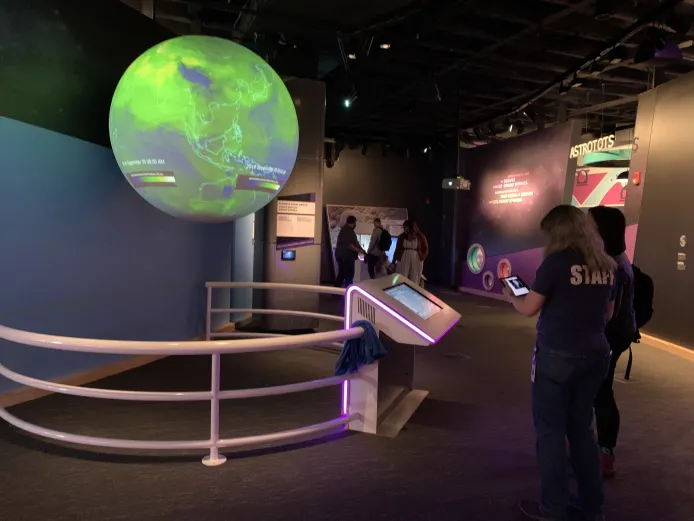 A Science on Sphere exhibit is mounted in a museum space. The circulation of dust video is displayed on the sphere.