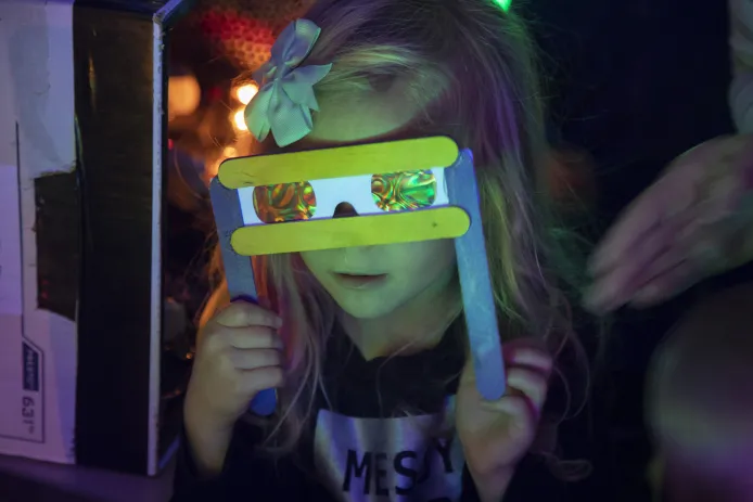 Young girl looks through light refraction glasses.
