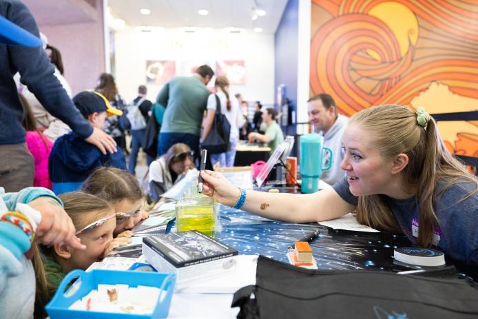 A student and scientist participate in Super Science Saturday activities