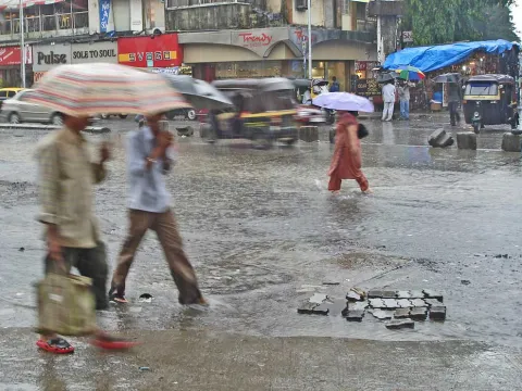 People walking in a flooded street in Mumbai, India in the rain