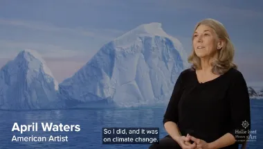 April Waters talks about her artwork with one of her paintings of Antarctic ice behind her.