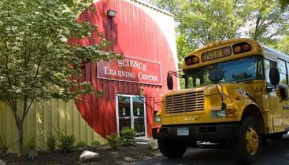 A photo of a yellow school bus parked outside a building that has a sign that reads "Science Learning Center"