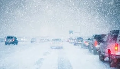 A photo of cars on a highway in the middle of a snowstorm. 
