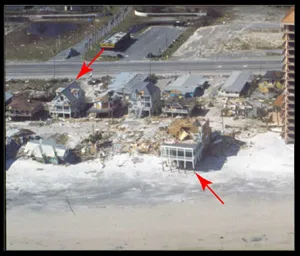 All of the houses are damaged and only two houses remain standing. There is sand and debris covering the ground around the houses.