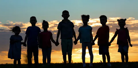 Silhouette of seven children holding hands