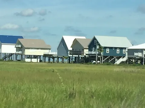 A photo of a line of homes that have stilts to elevate them from the ground.