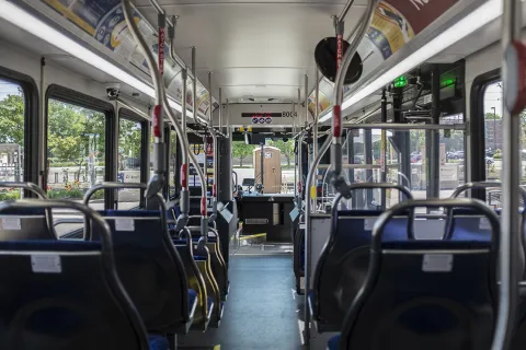 This is a photo from inside a public bus, looking towards the front of the bus with rows of seats on each side.